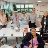 Group of elderly women and staff smiling together at a community center