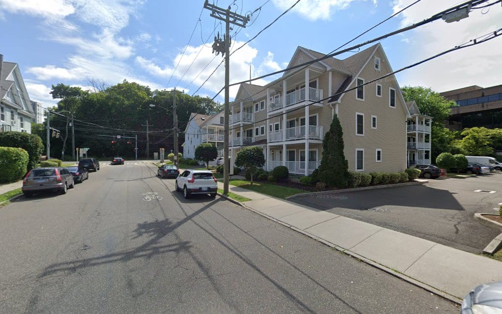 Quiet Connecticut residential street with multi-story apartment buildings nearby.