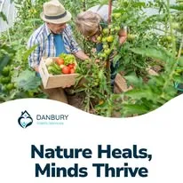 Two elderly adults harvesting fresh vegetables together in a lush garden.